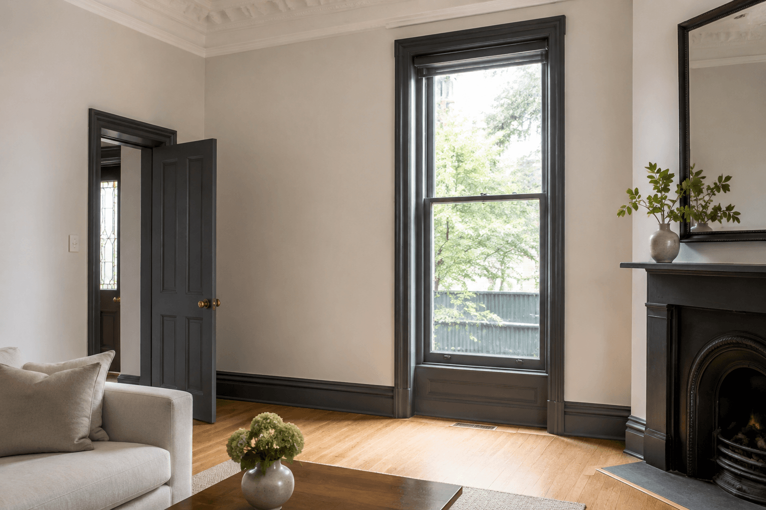 refreshed period living room with warm pale walls, detailed ceiling and dark painted door